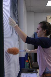 Nicole dusts the window blinds. Photo by Amparo Gil