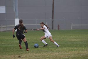 Junior defender Mikayla Wallace tries to avoid a Churchill forward. Photo by Jacob Dukes