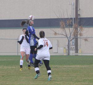 Junior Kyra Falcone leaps over a Madison defender to head the ball away. Photo by Jacob Dukes