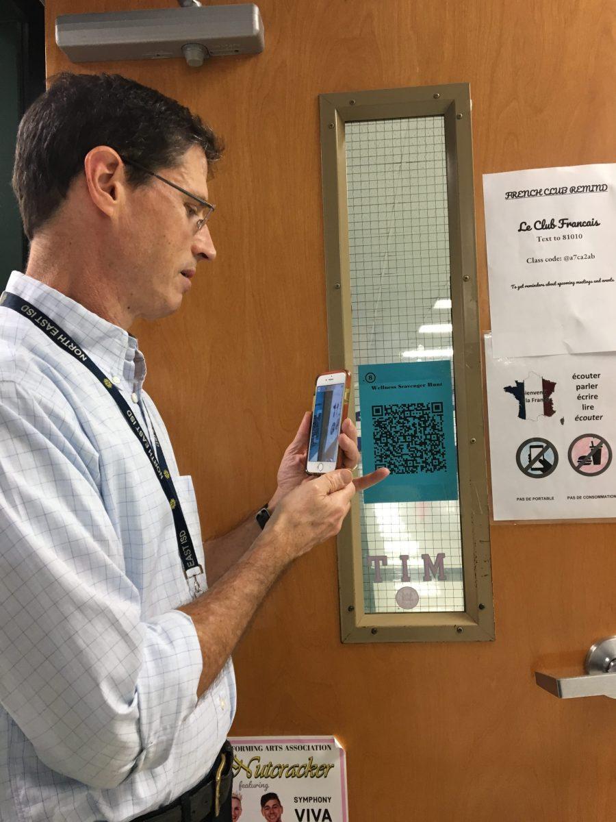 Mr.Curran is scanning one  of the QR codes.