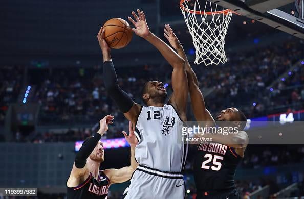 MEXICO CITY, MEXICO - DECEMBER 14: LaMarcus Aldrige #12 of the San Antonio Spurs shoots the ball against Mikal Bridges #25 of the Phoenix Suns and Frank Kaminsky #8 of the Phoenix Suns during a game between San Antonio Spurs and Phoenix Suns at Arena Ciudad de Mexico on December 14, 2019 in Mexico City, Mexico. (Photo by Hector Vivas/Getty Images)