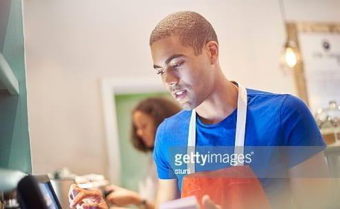 a young coffee shop worker entering the order into the a digital display screen